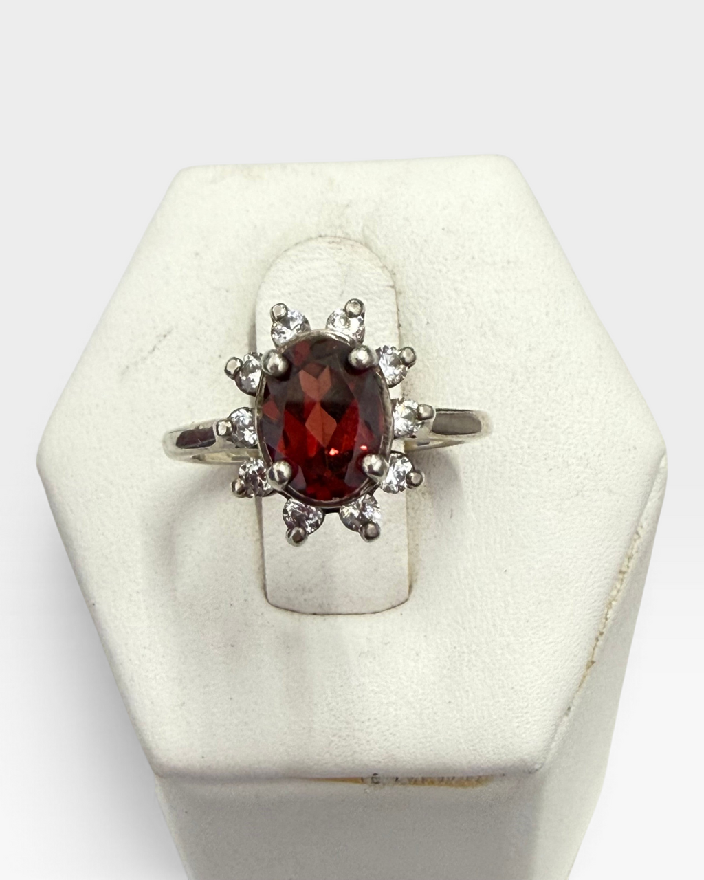Cavallaro Creations oval garnet halo ring with white accent stones set in a polished silver-tone band