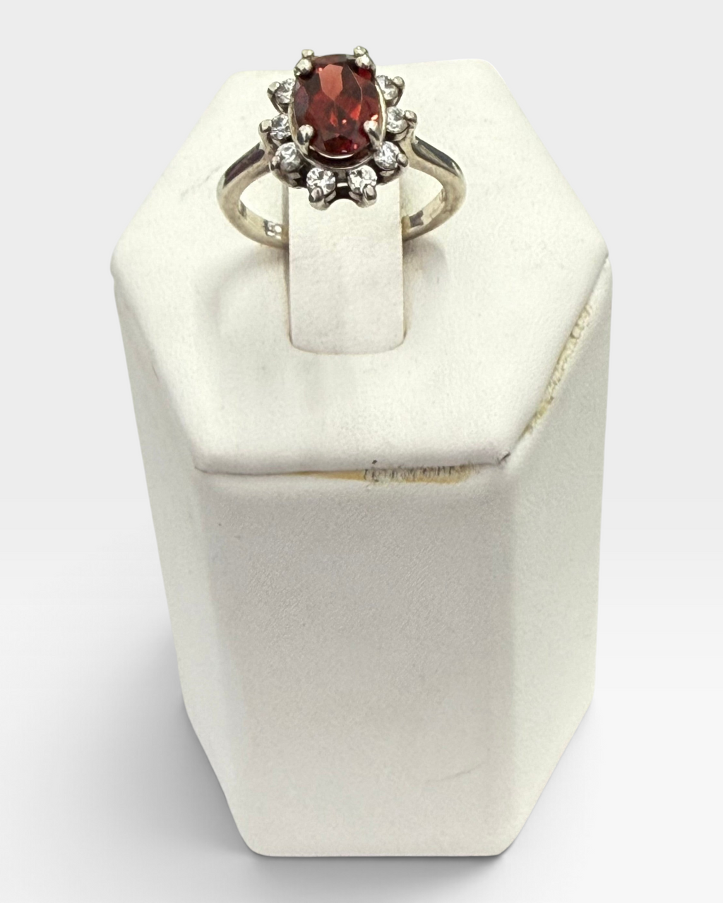 Cavallaro Creations oval garnet ring with a sparkling white stone halo set in a polished silver-tone band.