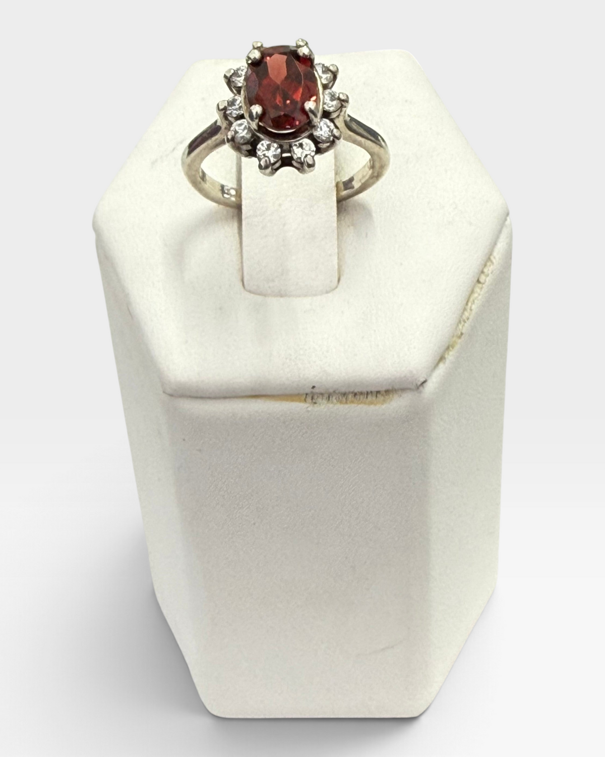 Cavallaro Creations oval garnet ring with a sparkling white stone halo set in a polished silver-tone band.